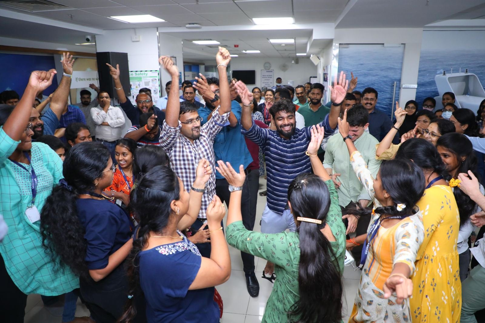 Colleagues dancing with arms in the air on the office floor