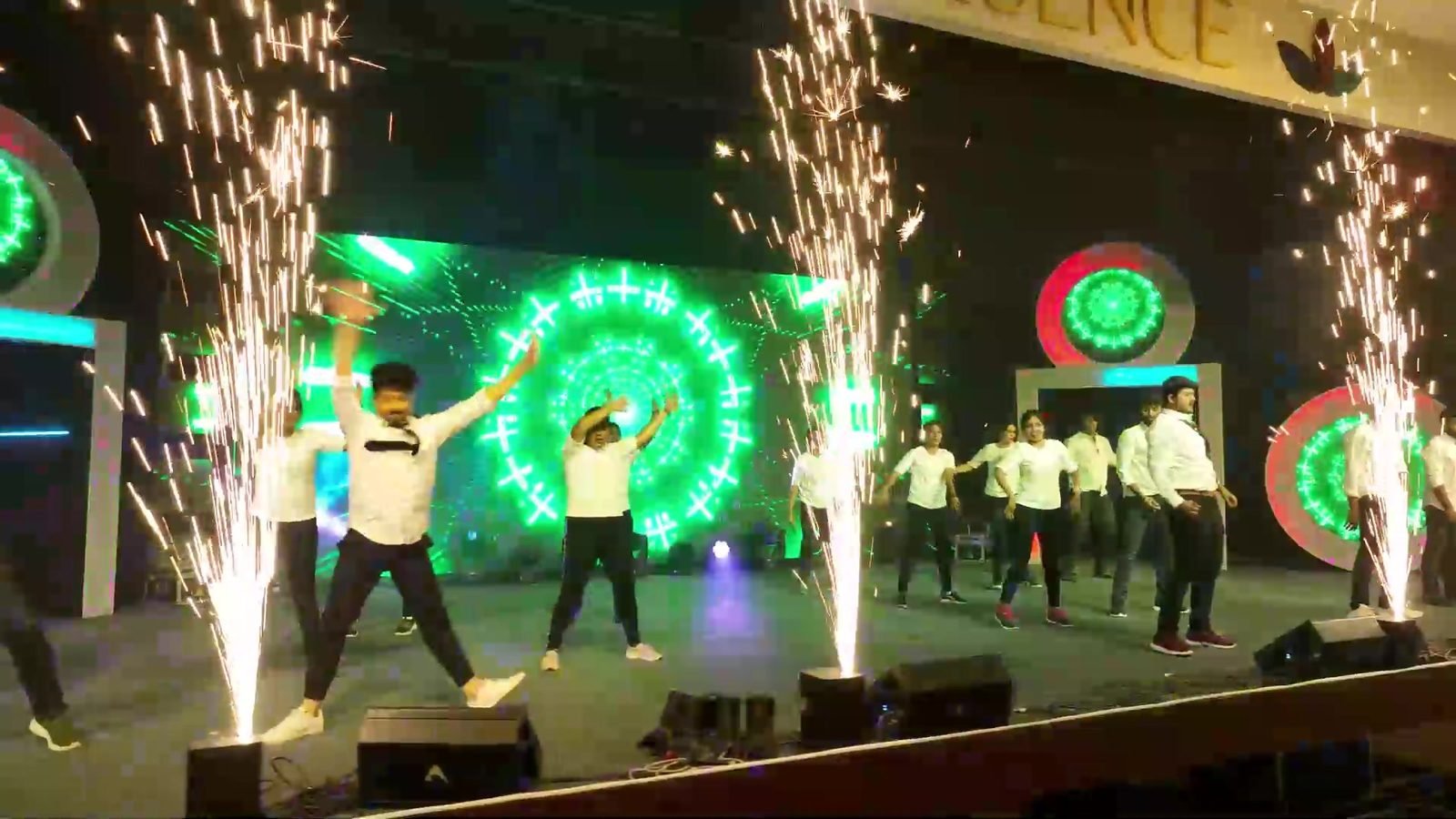 Colleagues dancing on stage between sparkler fountains